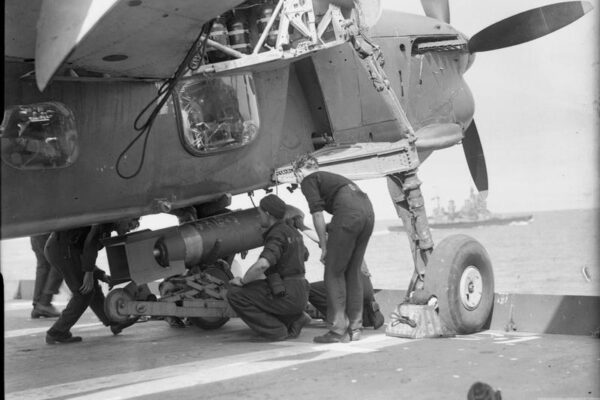 Fairey Barracuda being loaded with a bomb © IWM A 24784 THE ROYAL NAVY DURING THE SECOND WORLD WAR (A 24784) Bombing up a Fairey Barracuda with a 1600 lb bomb on board HMS FORMIDABLE at sea. An unidentified battleship can be seen sailing in the background. Copyright: © IWM. Original Source: http://www.iwm.org.uk/collections/item/object/205187218