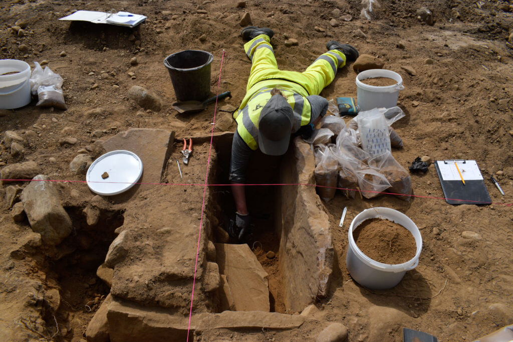 An archaeologist excavates a Bronze Age cist An archaeologist excavates a Bronze Age cist