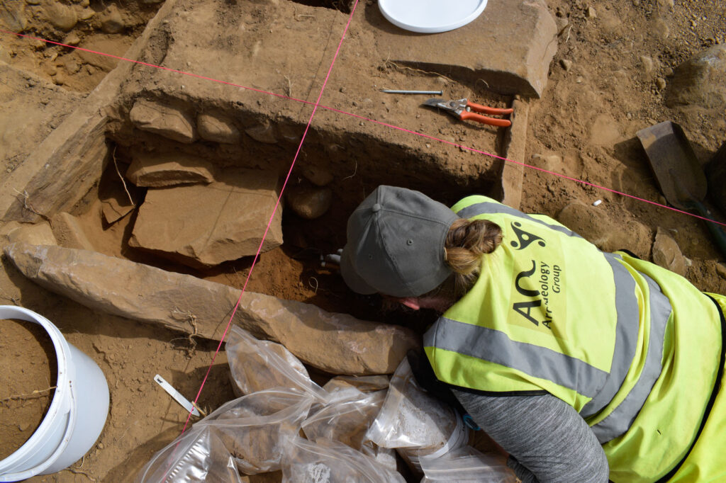 An archaeologist excavates a Bronze Age cist An archaeologist excavates a Bronze Age cist